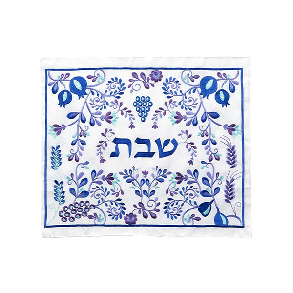 Ce Couvre Hallot Bleu-Blanc est décoré de motifs représentant des épis de blés, des grappes de raisins, des grenades et des fleurs. Le tout entoure la broderie en lettre hébraïque du mot Shabbat.